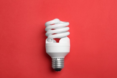 New fluorescent lamp bulb on red background, top view