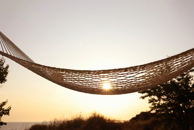 Photo of Empty hammock hanging outdoors. Time to relax