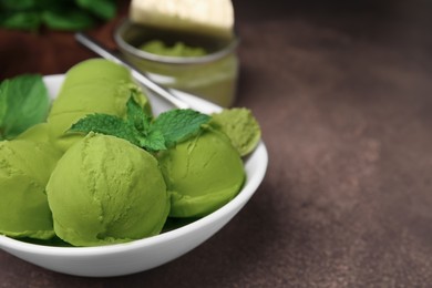 Photo of Tasty matcha ice cream and spoon with powder in bowl on brown table, closeup. Space for text