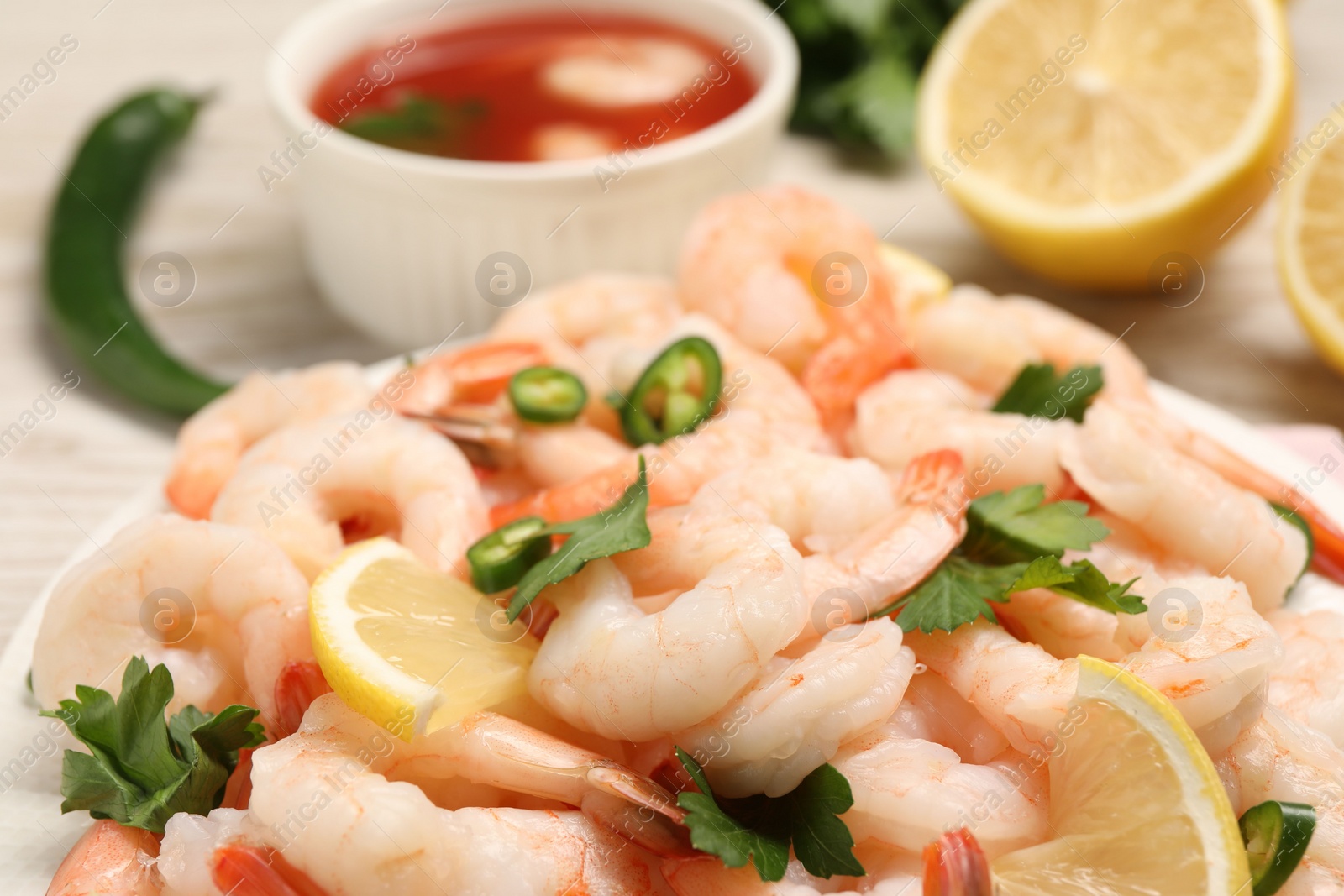 Photo of Tasty boiled shrimps with cocktail sauce, chili and parsley on table, closeup