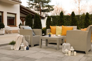 Beautiful rattan garden furniture, soft pillows and different decor elements in backyard