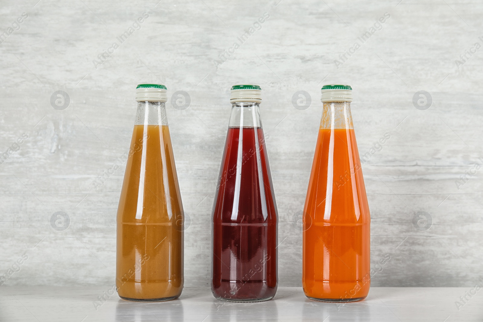 Photo of Bottles with different drinks on table against color background