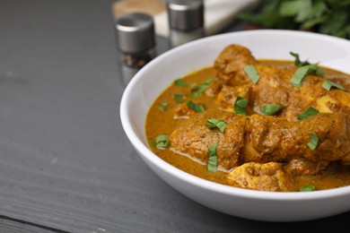 Photo of Delicious chicken with curry sauce on grey wooden table, closeup. Space for text