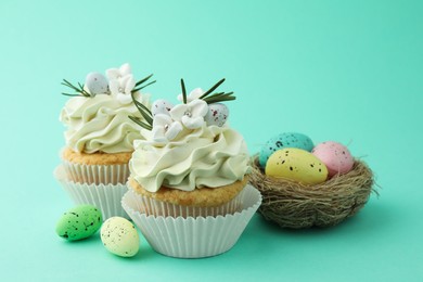 Tasty Easter cupcakes with vanilla cream and festive decor on turquoise background