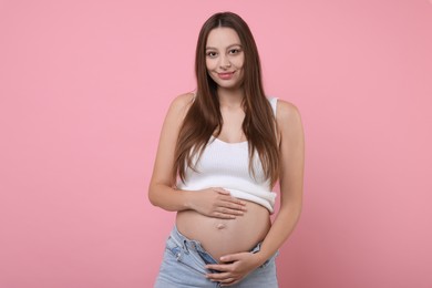 Photo of Beautiful pregnant woman with long hair on pink background