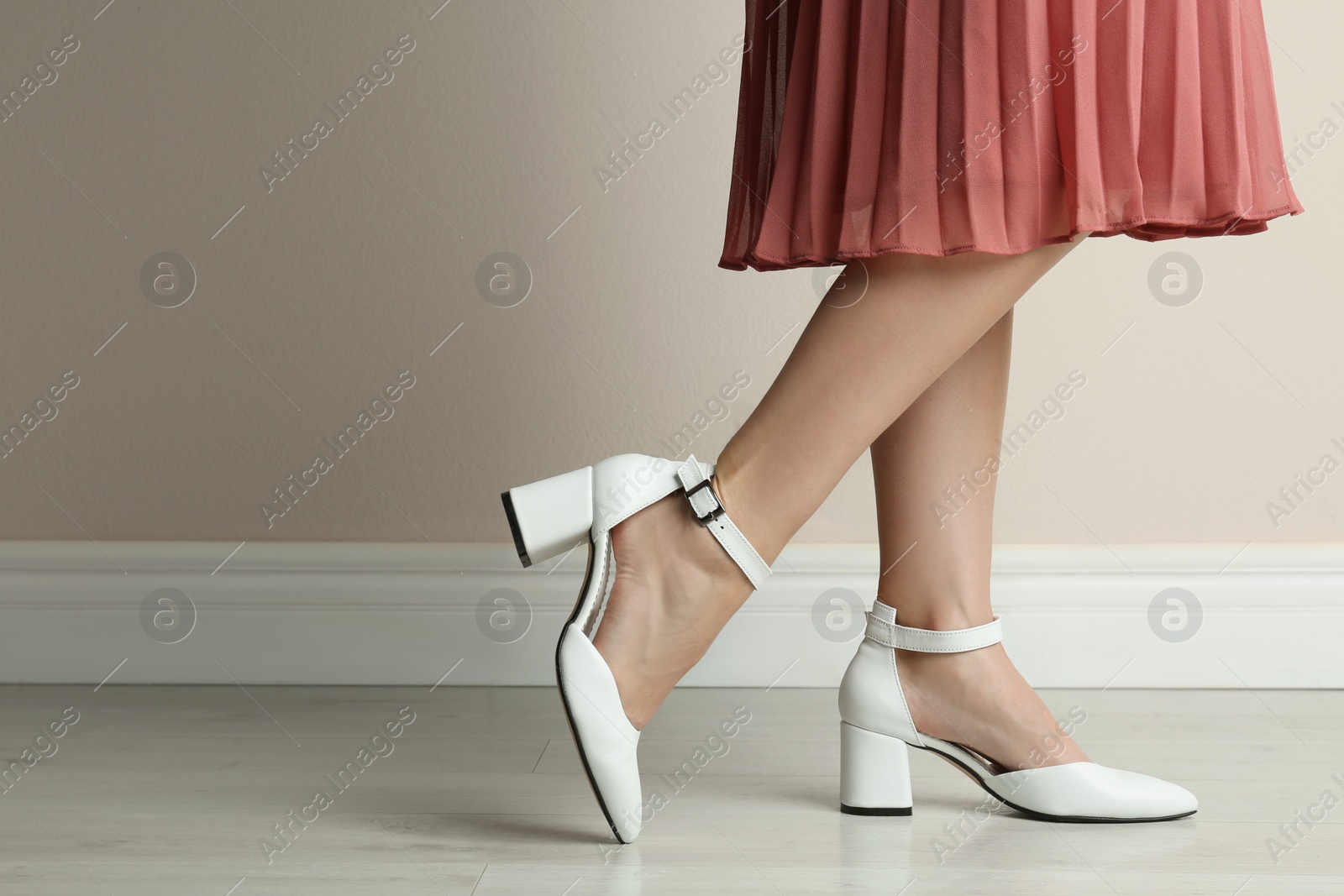 Photo of Woman wearing stylish shoes near beige wall indoors, closeup