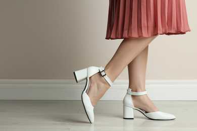 Photo of Woman wearing stylish shoes near beige wall indoors, closeup