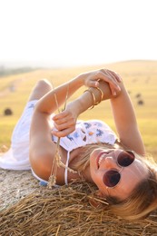 Photo of Beautiful hippie woman with spikelets on hay bale in field