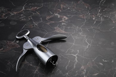 One wing corkscrew on black marble table. Space for text