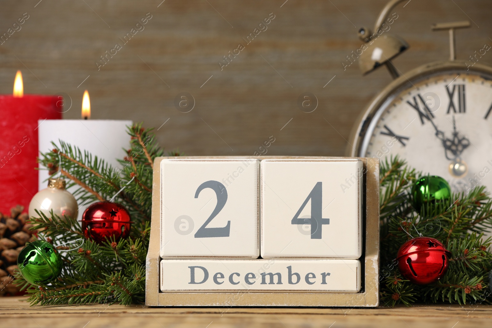 Photo of December 24 - Christmas Eve. Wooden block calendar, alarm clock and festive decor on table