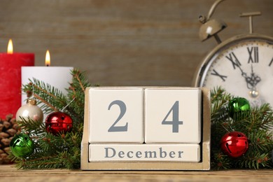 Photo of December 24 - Christmas Eve. Wooden block calendar, alarm clock and festive decor on table