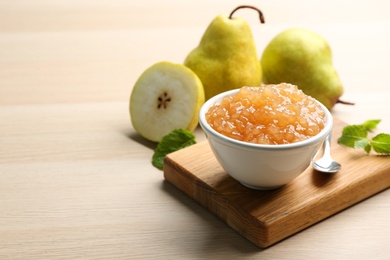 Photo of Tasty homemade pear jam and fresh fruits on wooden table. Space for text