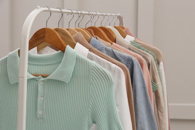 Rack with stylish clothes near light wall