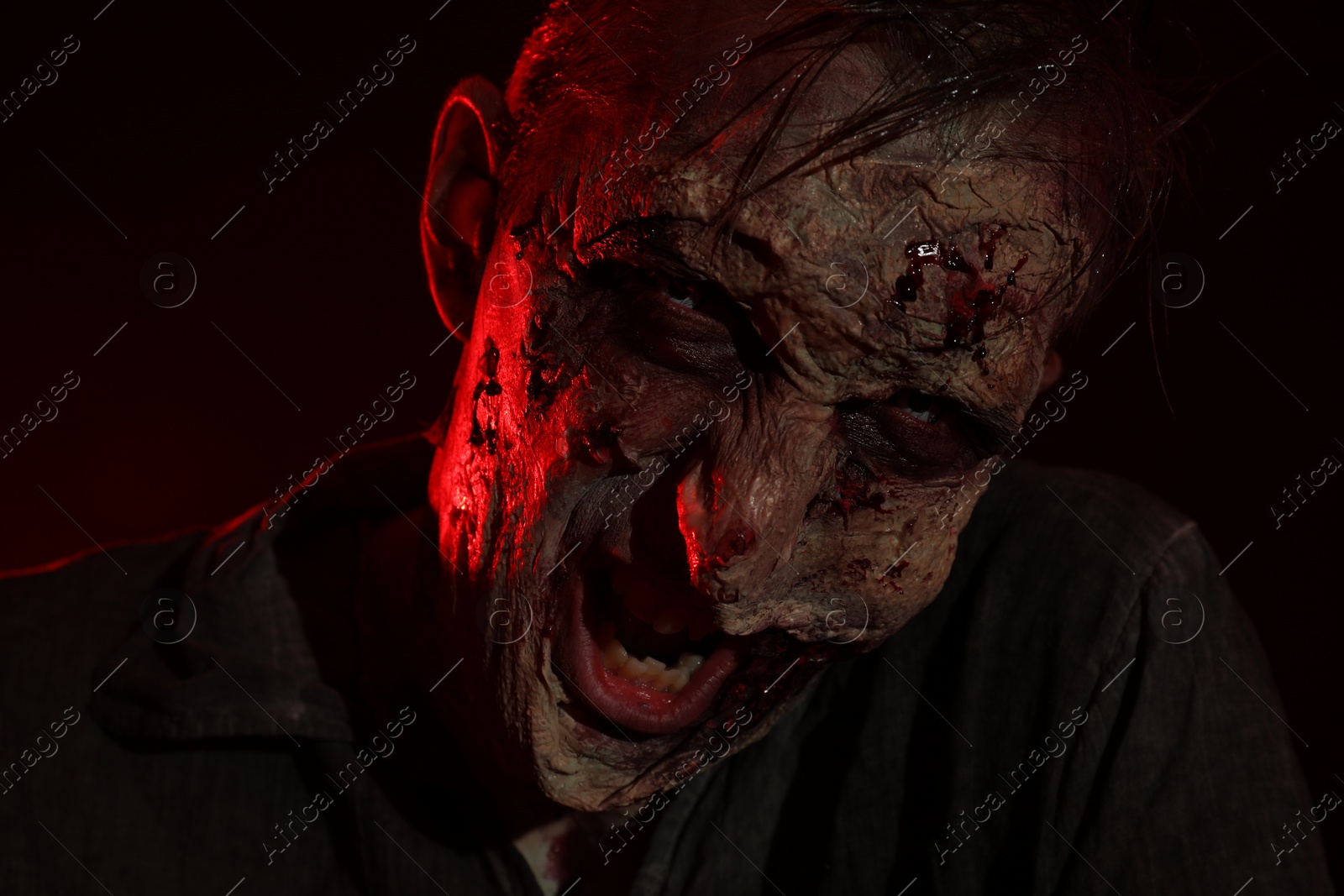 Photo of Scary zombie on dark background, closeup. Halloween monster