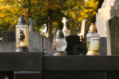 Photo of Different grave lanterns on granite tombstone outdoors. Funeral ceremony