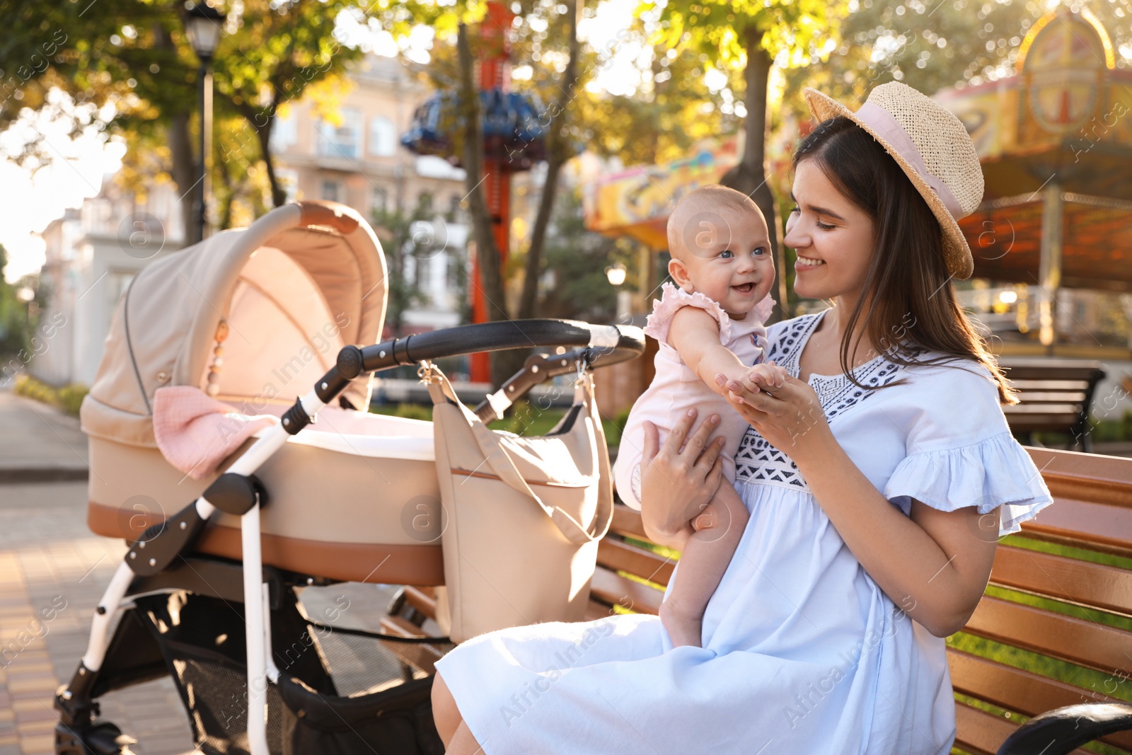 Photo of Happy mother with baby sitting on bench in park