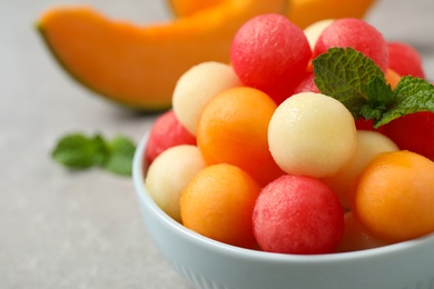 Melon balls and mint in bowl on grey table, closeup