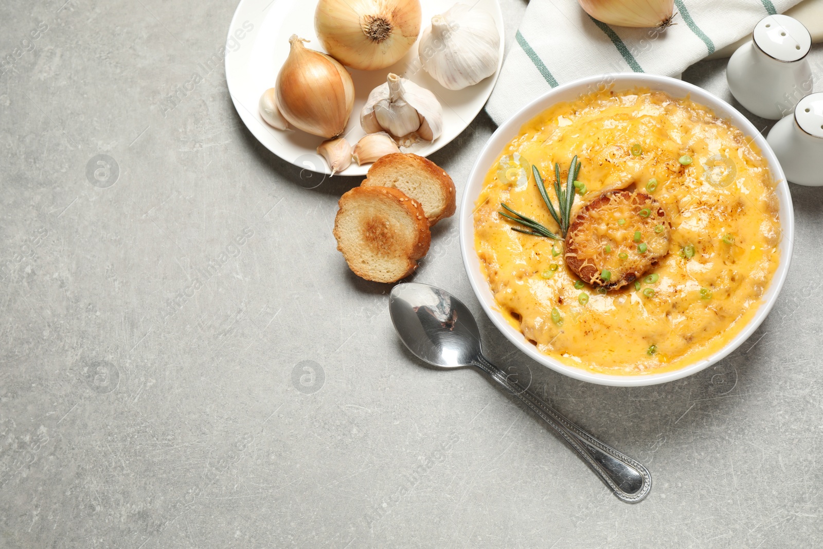 Photo of Tasty homemade French onion soup on grey table, flat lay. Space for text