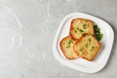 Photo of Slices of toasted bread with garlic and herb on light grey marble table, top view. Space for text