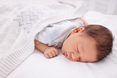 Cute newborn baby sleeping under white plaid in crib