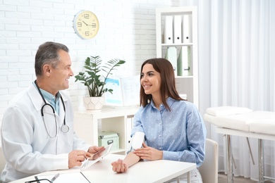 Doctor checking young woman's pulse with medical device in hospital