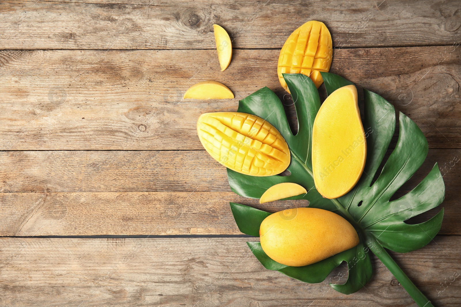 Photo of Flat lay composition with mango and tropical leaf on wooden background. Space for text