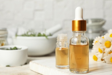 Photo of Composition with bottles of chamomile essential oil on table. Space for text