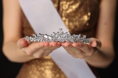 Photo of Woman in dress holding tiara on black background, closeup