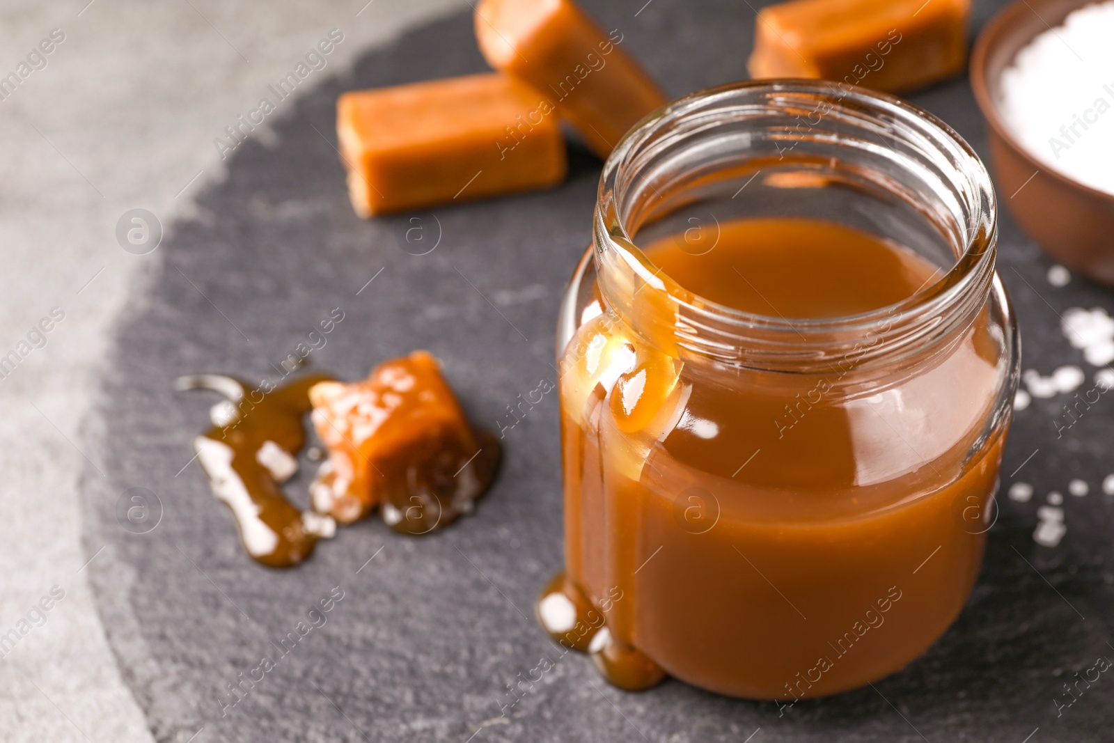 Photo of Delicious salted caramel in jar on slate board