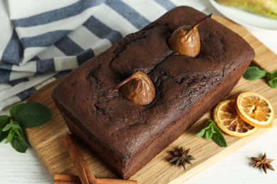 Photo of Tasty pear bread with mint, spices and dried orange slices on table. Homemade cake