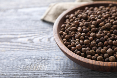 Photo of Peppercorns on light grey wooden table, closeup