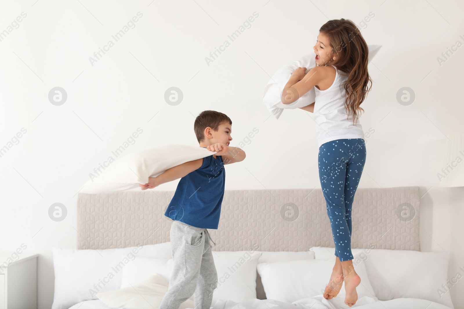 Photo of Happy children having pillow fight in bedroom