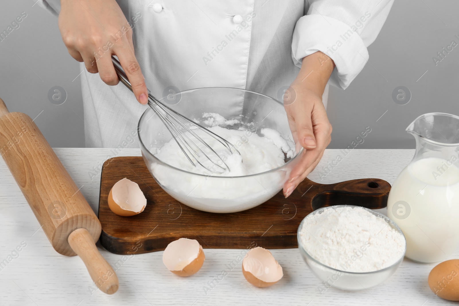 Photo of Woman whipping egg whites at wooden table, closeup. Baking pie