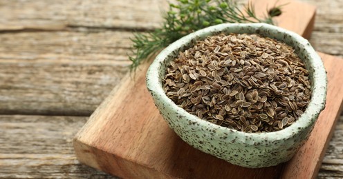 Image of Dill seeds in bowl on wooden table, closeup. Banner design with space for text