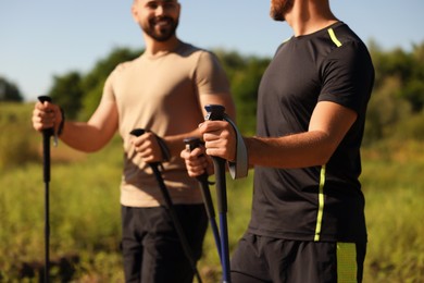 Men practicing Nordic walking with poles outdoors on sunny day, selective focus
