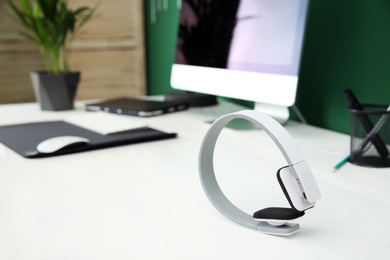 Photo of Stylish headphones on office table. Space for text