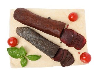 Delicious dry-cured beef basturma with basil and tomatoes on white background, top view