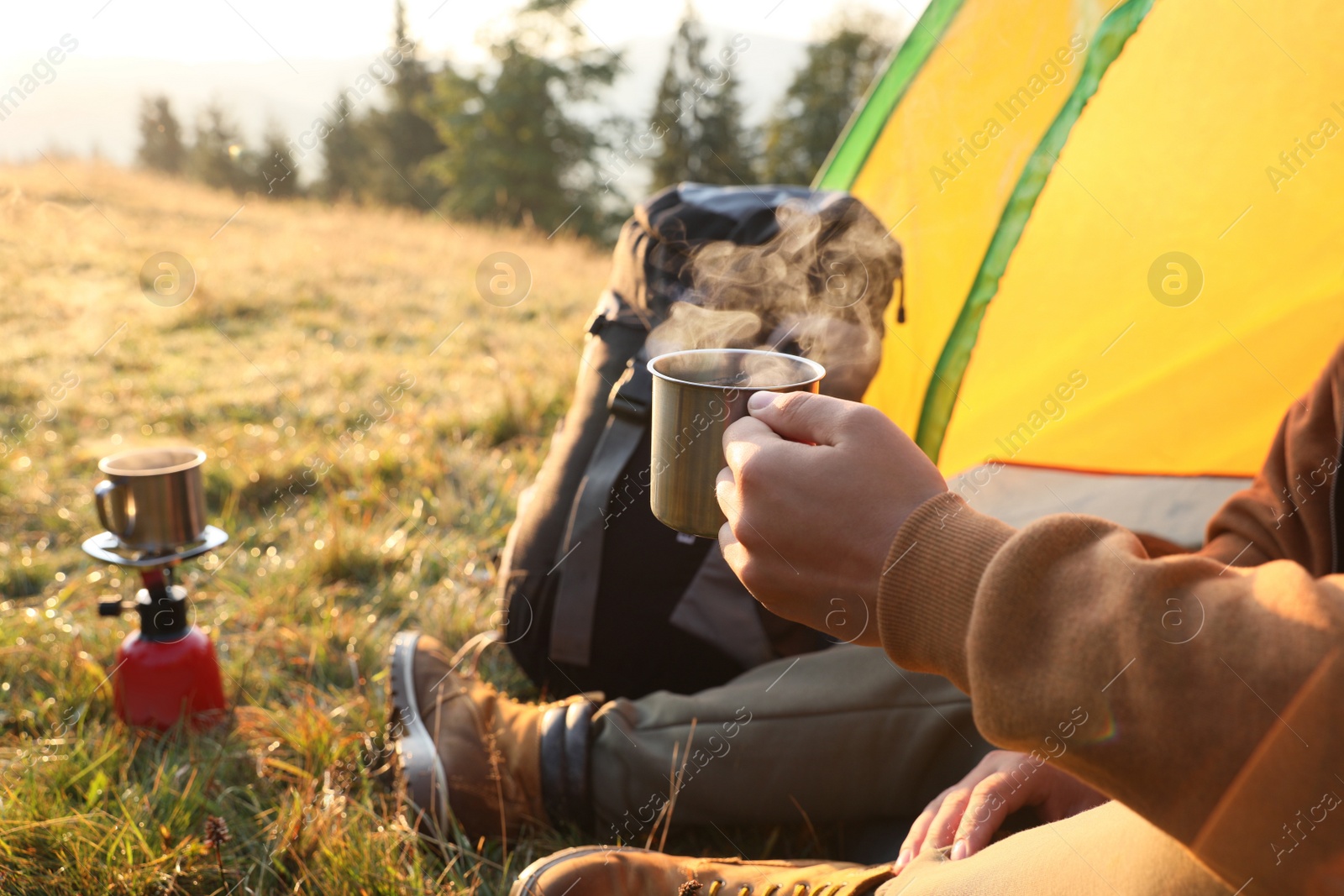 Photo of Man with cup of hot drink in camping tent, closeup