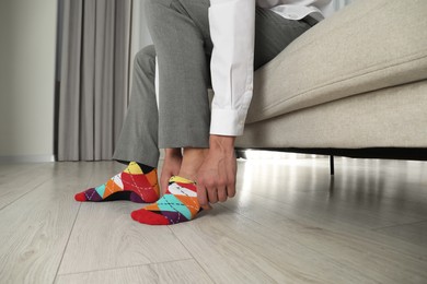 Man putting on colorful socks indoors, closeup