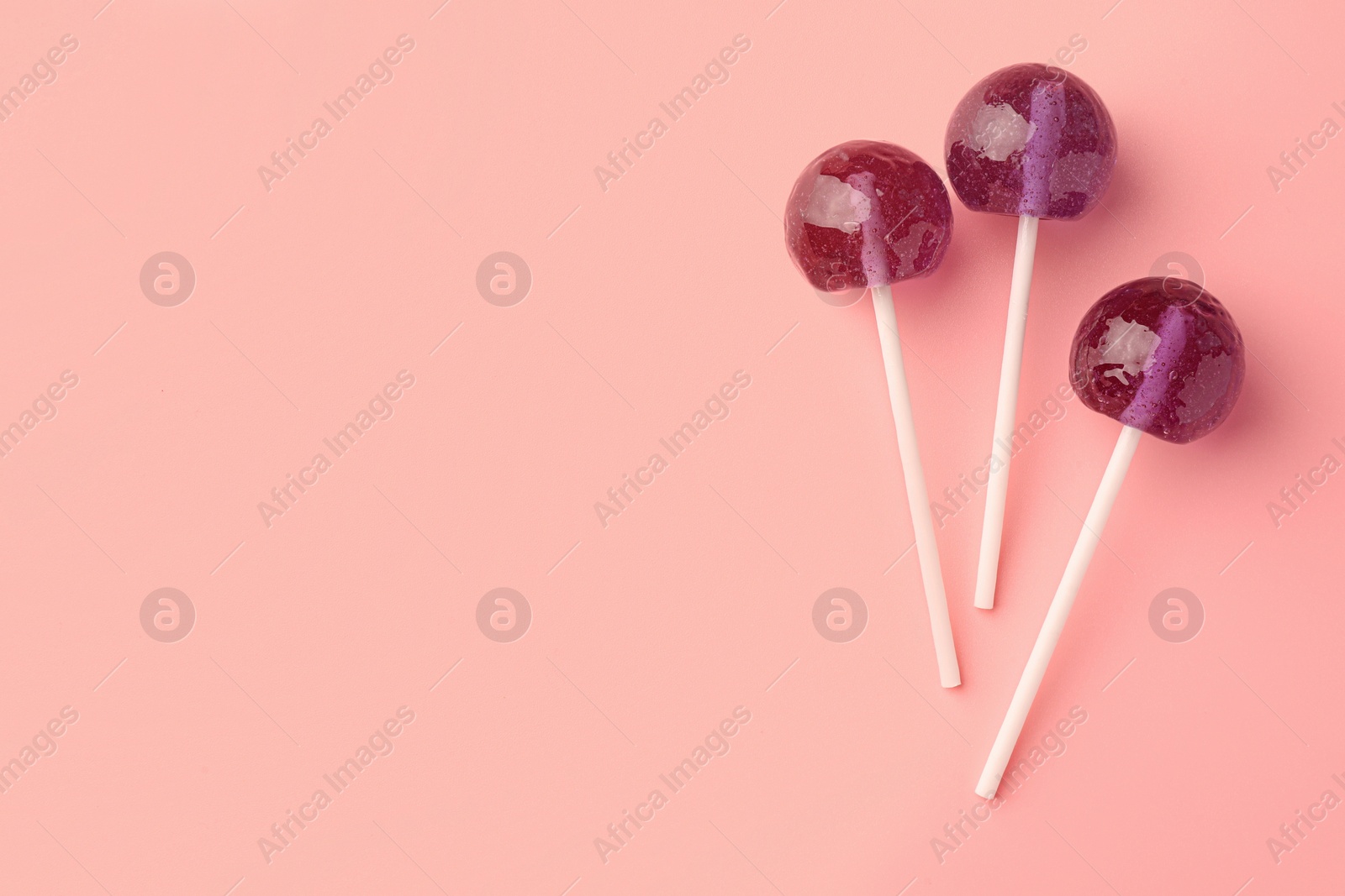 Photo of Tasty lollipops on pink background, flat lay. Space for text