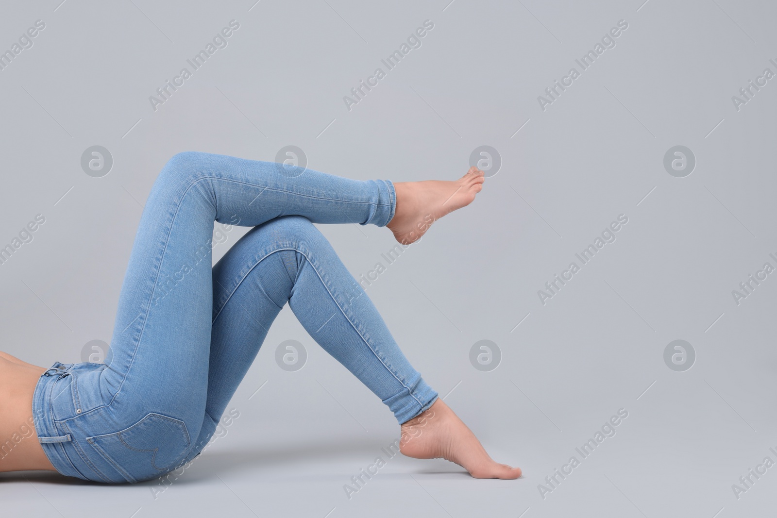 Photo of Woman wearing stylish jeans on light gray background, closeup. Space for text