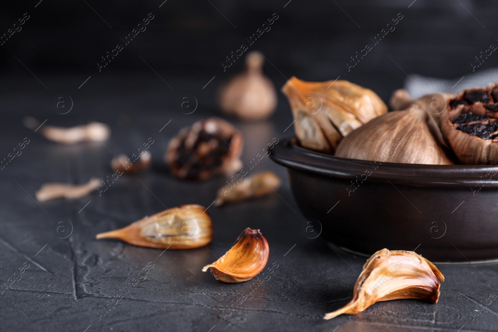 Photo of Bowl with aged black garlic on table. Space for text