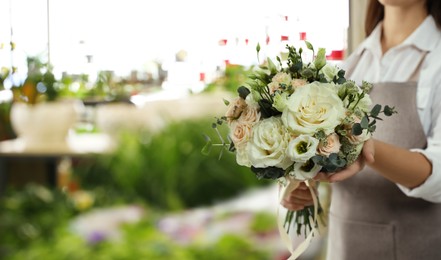 Florist holding beautiful wedding bouquet in flower shop, closeup. Space for text 