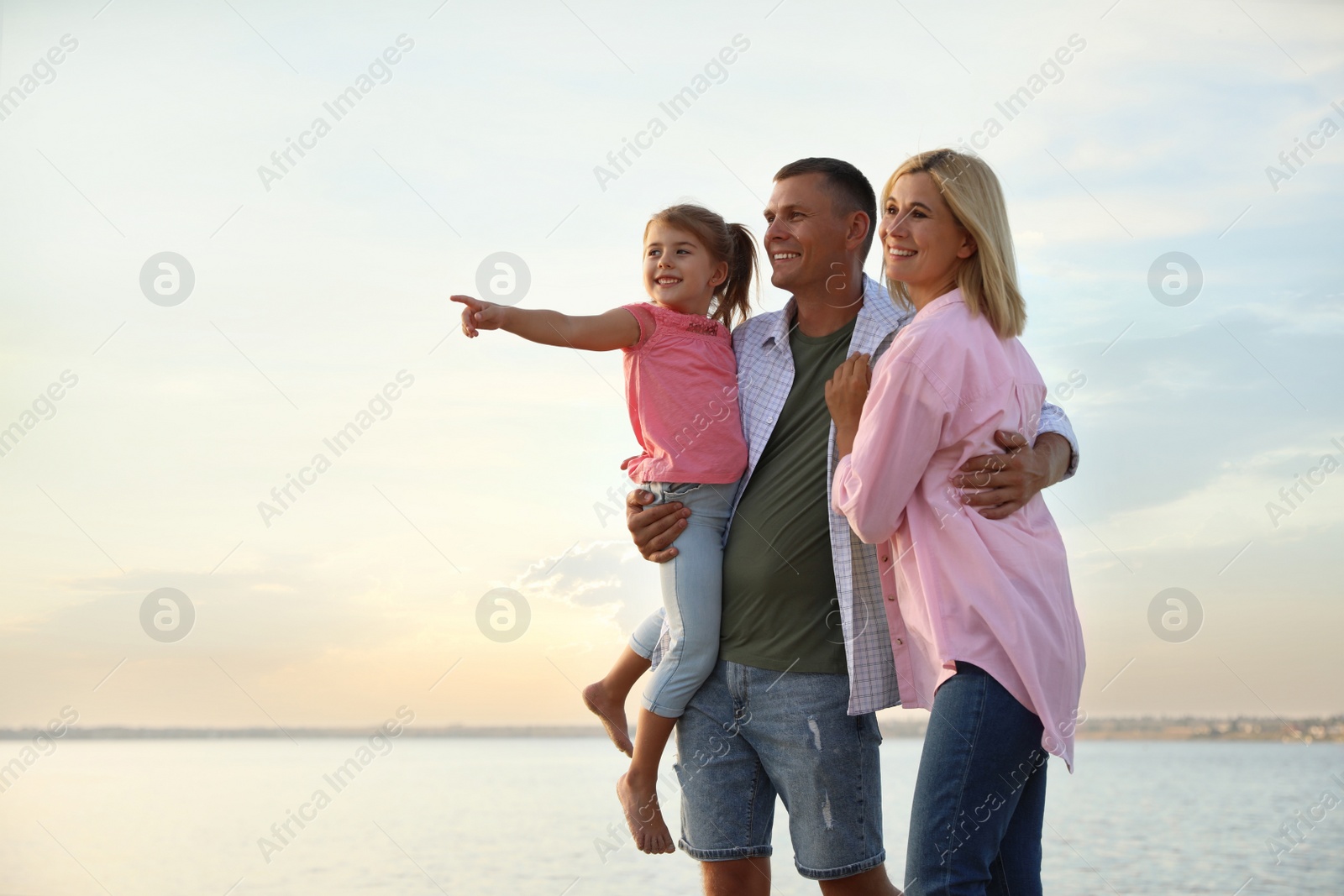 Photo of Happy parents with their child on beach. Spending time in nature