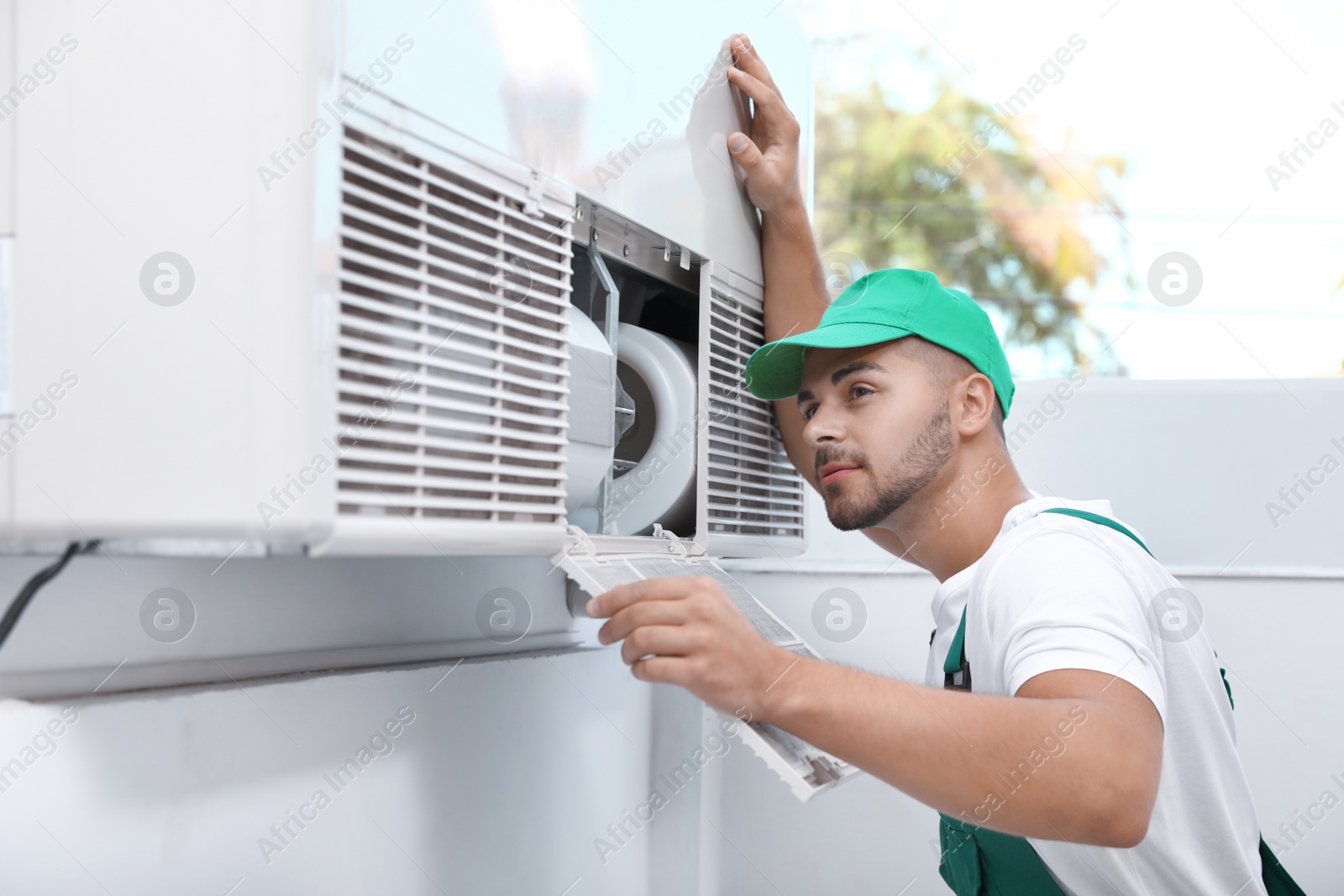 Photo of Professional technician maintaining modern air conditioner indoors