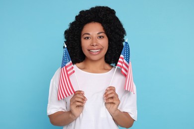 4th of July - Independence Day of USA. Happy woman with American flags on light blue background