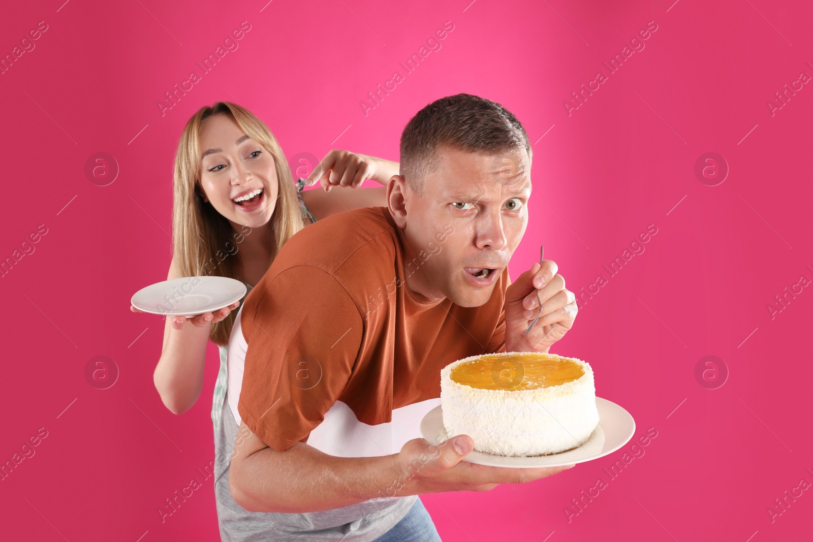 Photo of Greedy man hiding tasty cake from woman on pink background