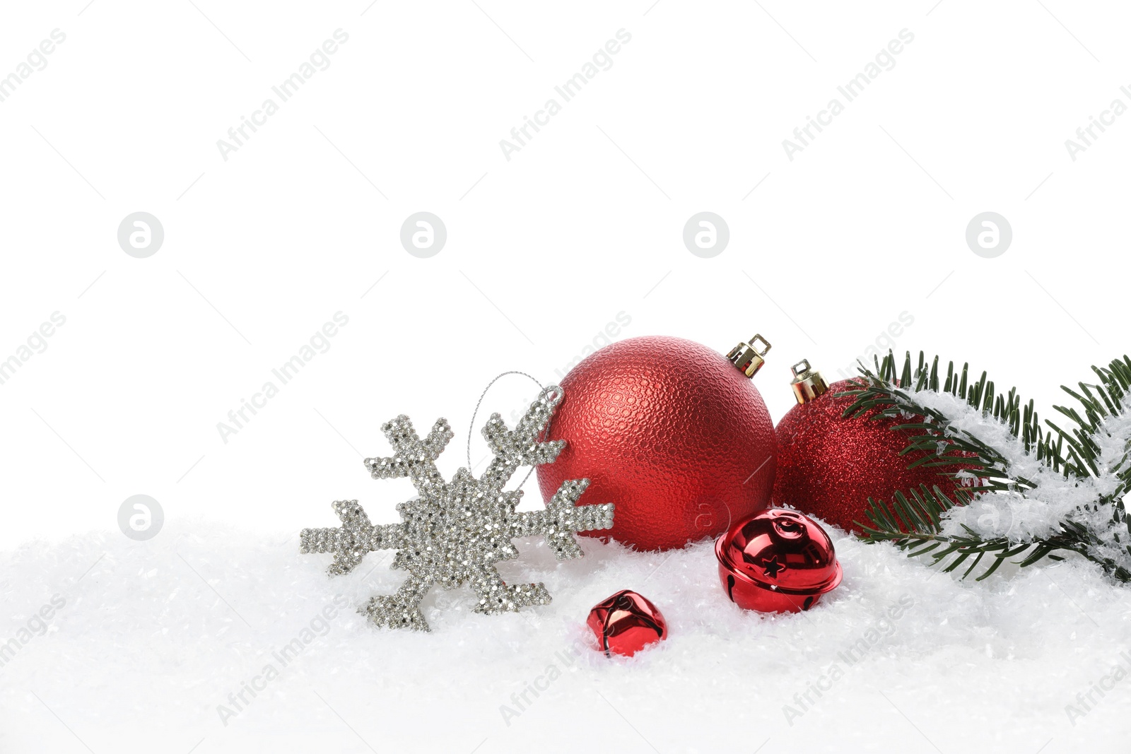 Photo of Beautiful red Christmas balls, fir tree branch and other festive decor on snow against white background