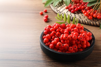 Plate with fresh ripe rowan berries on wooden table, space for text