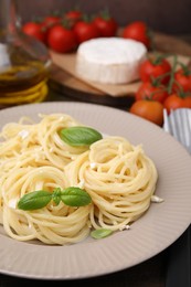 Photo of Delicious pasta with brie cheese and basil leaves on table, closeup